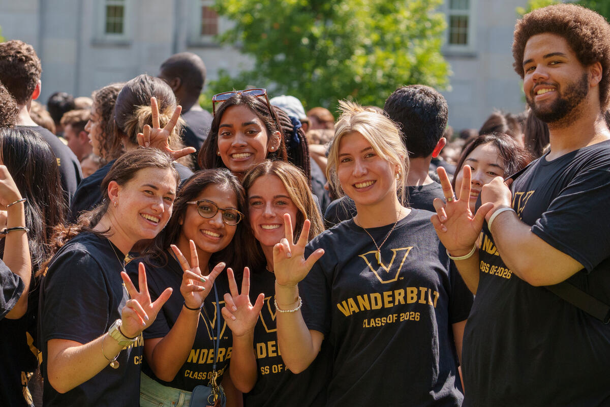 Four first-year students wearing matching black Vanderbilt shirts show the VU hand sign at Move-in