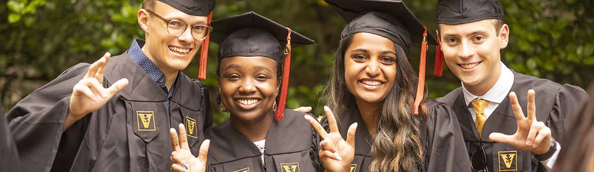 students in graduation attire showing the VU handsign